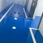 Piso epóxi azul com faixas brancas em área industrial