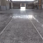 Piso de concreto lapidado refletindo as luminárias