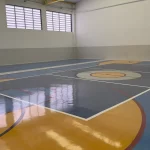 Quadra coberta com piso em resina azul, laranja e cinza