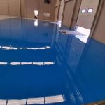 Piso epóxi azul brilhante refletindo a iluminação do galpão
