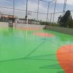 Quadra externa com piso em poliuretano verde e laranja