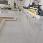 Área industrial com piso em poliuretano cinza claro e máquinas