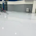 Piso epóxi branco em galpão com máquinas ao fundo