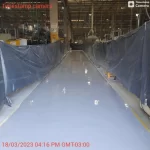 Corredor de fábrica com piso epóxi cinza claro e lonas de proteção