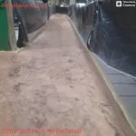 Corredor com concreto lixado e lonas de proteção antes do epóxi