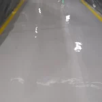 Corredor com piso epóxi cinza claro brilhante e faixas amarelas