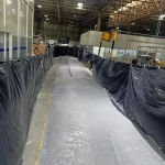 Corredor de fábrica com lonas de proteção e piso epóxi cinza brilhante