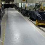 Corredor industrial isolado com lonas e piso epóxi cinza com faixa amarela