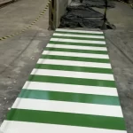 Faixa de pedestres verde e branca aplicada sobre piso epóxi