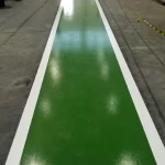 Faixa de circulação verde com bordas brancas em piso epóxi