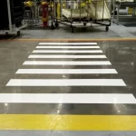 Faixa de pedestres branca e amarela em piso epóxi industrial
