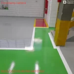 Piso epóxi verde com bordas brancas junto a pilar amarelo