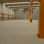 Concreto preparado em galpão com estrutura amarela antes do epóxi