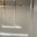 Piso epóxi cinza claro de alto brilho com reflexo das luminárias