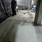Piso industrial em preparação com mangueira e resíduos