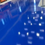 Piso em poliuretano azul refletindo as luminárias