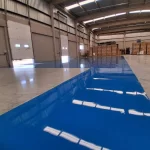 Piso epóxi azul em galpão com estantes ao fundo