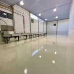 Piso epóxi cinza claro em área de produção com bancadas