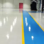 Corredor em epóxi azul com faixas amarelas em piso epóxi branco