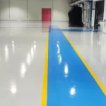 Faixa de circulação em epóxi azul com bordas amarelas sobre piso branco