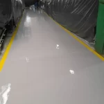 Corredor com piso epóxi cinza e faixas amarelas