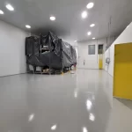 Piso em uretano cinza claro junto a máquina e porta amarela