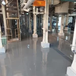 Área industrial com pilares brancos e piso em uretano cinza