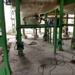 Área industrial com tubulações verdes e piso em preparação