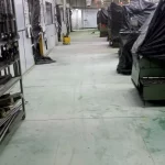 Piso verde desgastado em área industrial antes da reforma