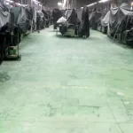 Piso verde desgastado entre máquinas industriais