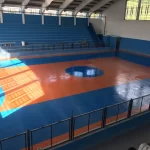 Quadra de ginásio em poliuretano laranja e azul iluminada pelo sol
