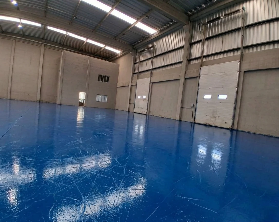 Antes: galpão com concreto e piso epóxi azul em aplicação